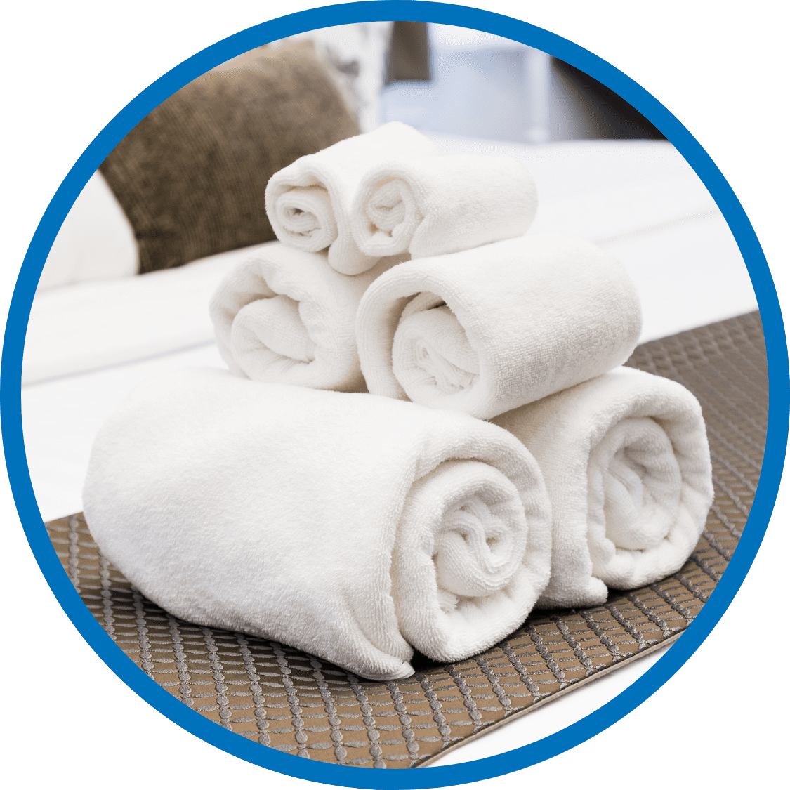 Neatly folded white towels stacked on a freshly made bed in a hospitality business