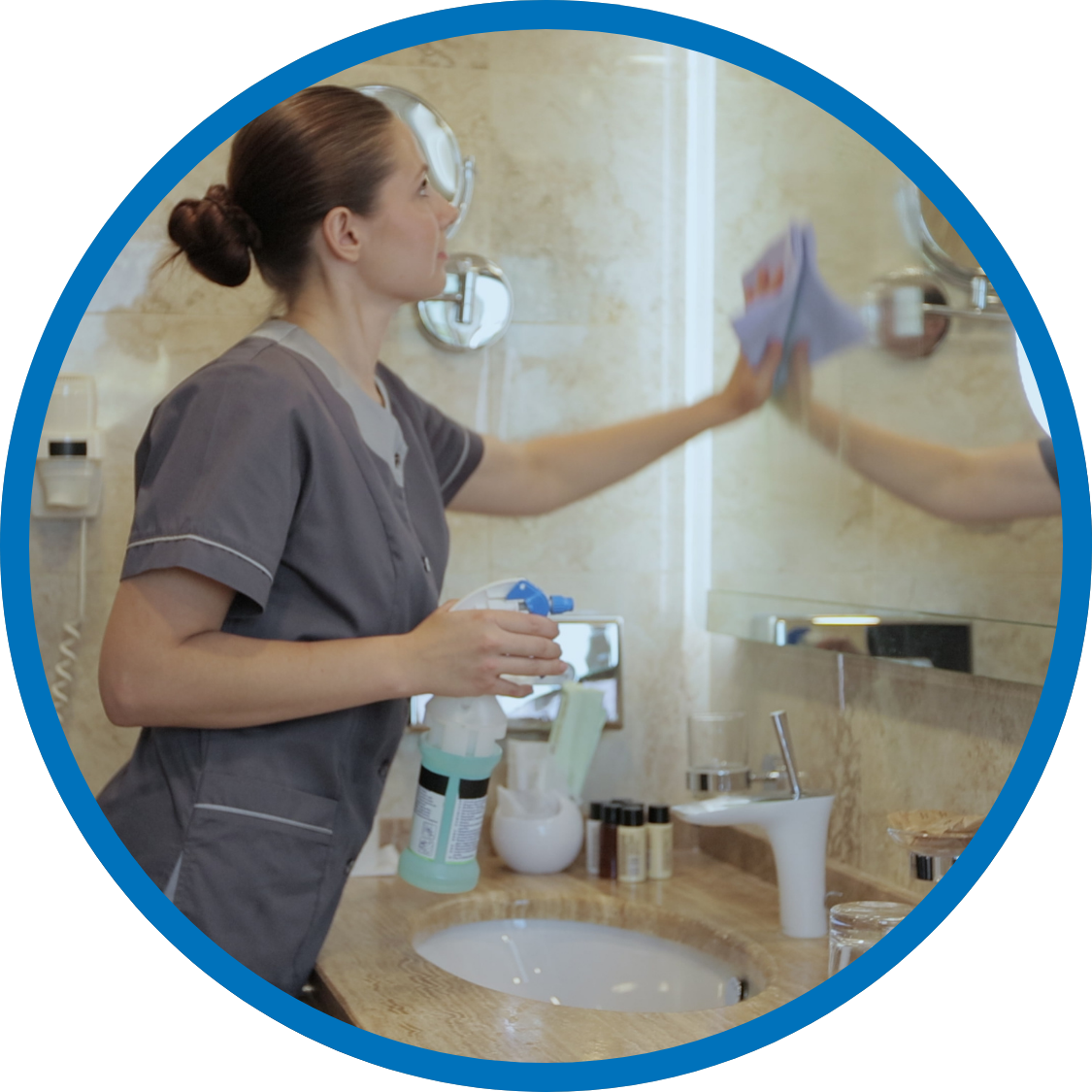 Hotel staff wiping mirror and cleaning bathroom after guest stay