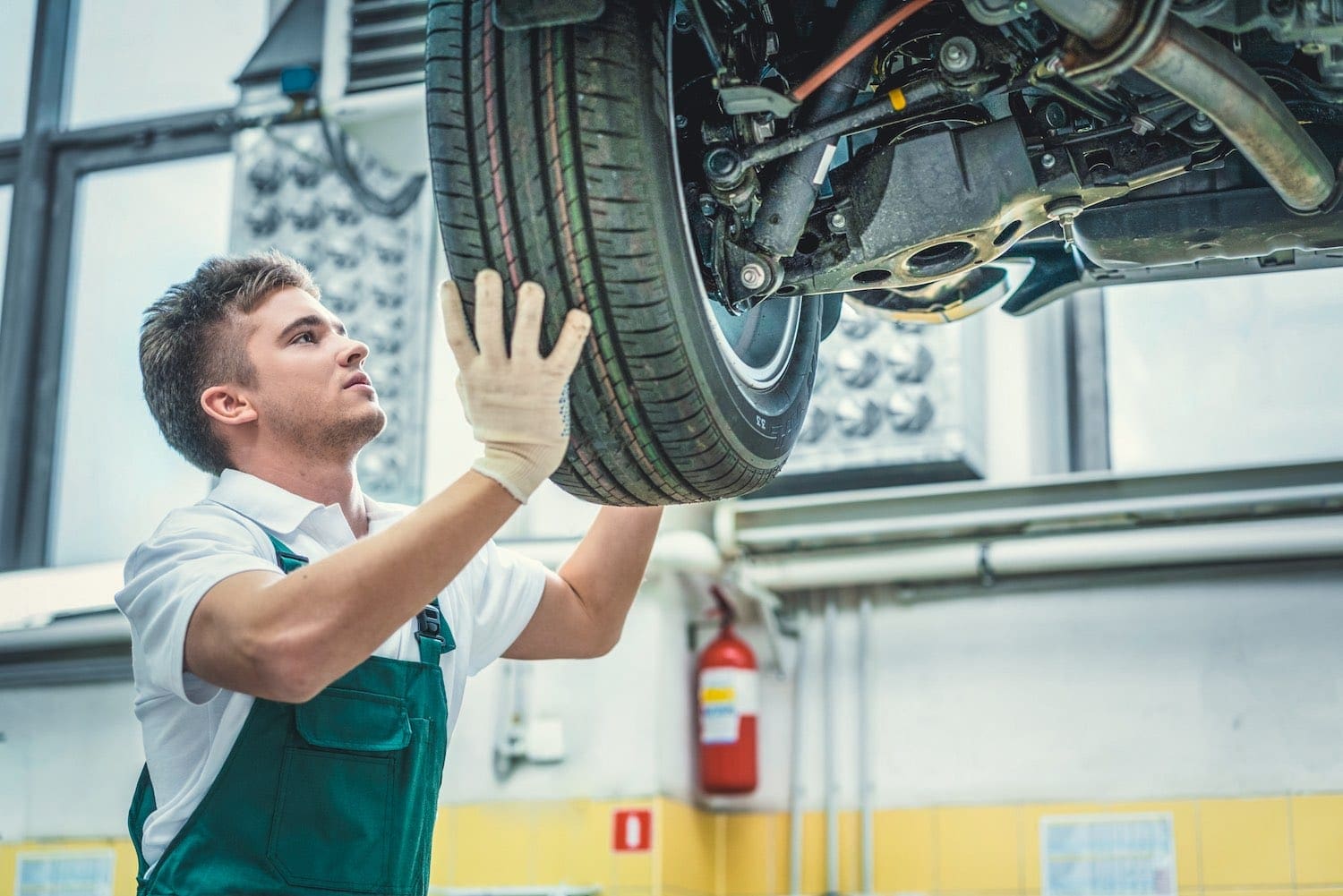 Uniformed man adjusting tire on car